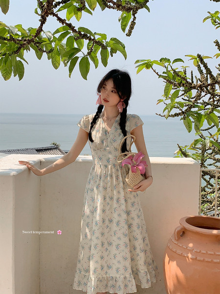 Woman wearing a light floral dress outdoors by the sea