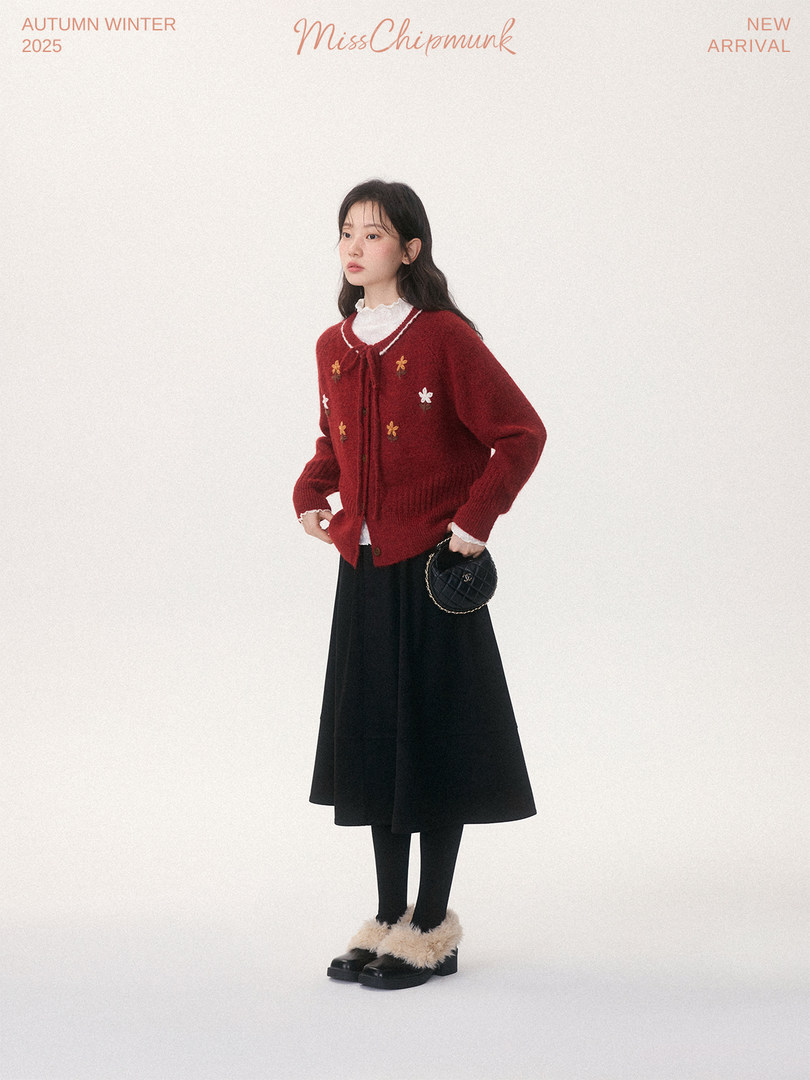 Model wearing a red embroidered cardigan with a black skirt and fuzzy shoes