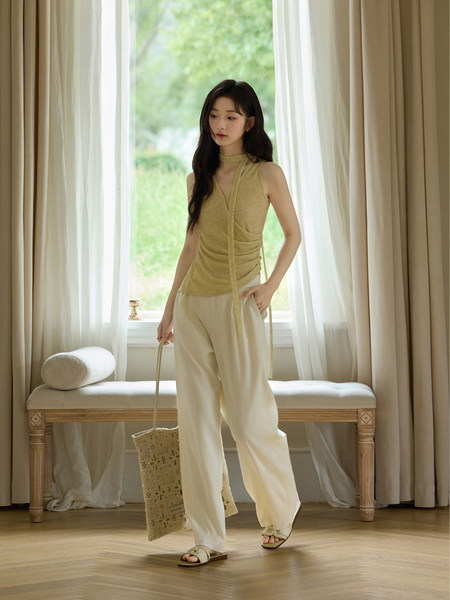 Model wearing a sleeveless wrap top with wide-leg pants in a soft neutral outfit