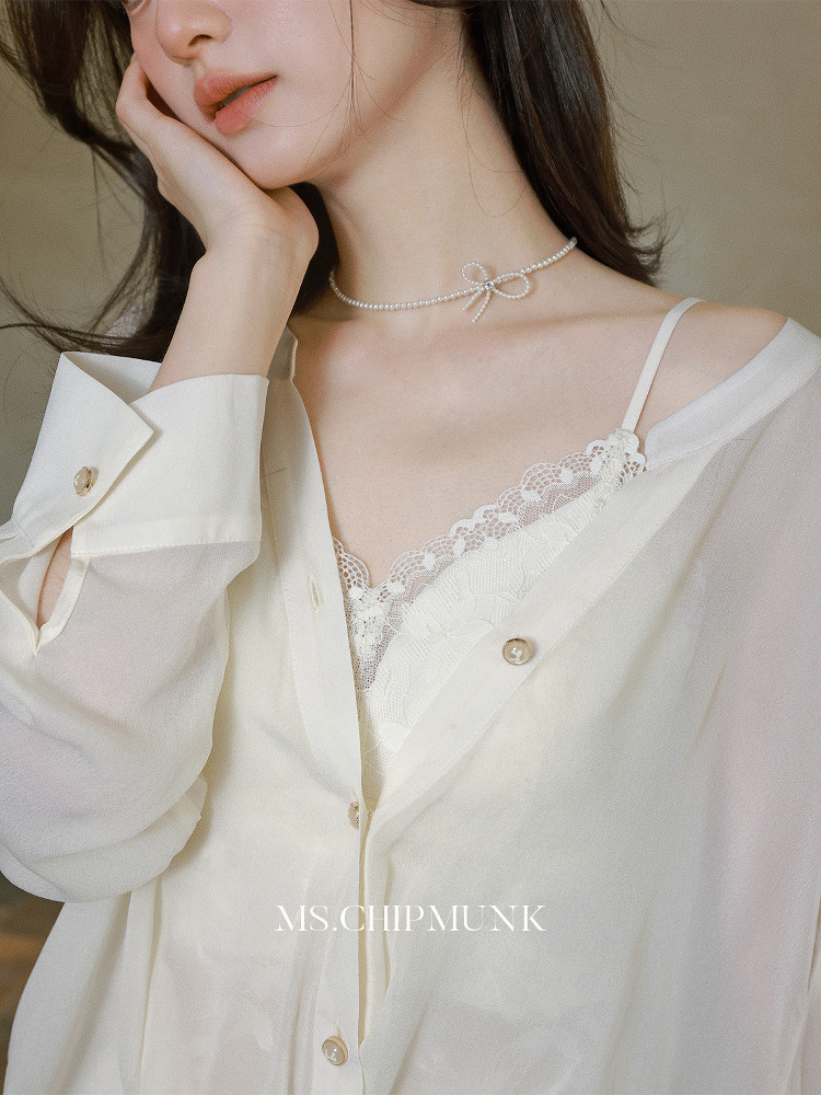 Model wearing an off-white oversized button-up shirt over a lace camisole with a pearl choker necklace