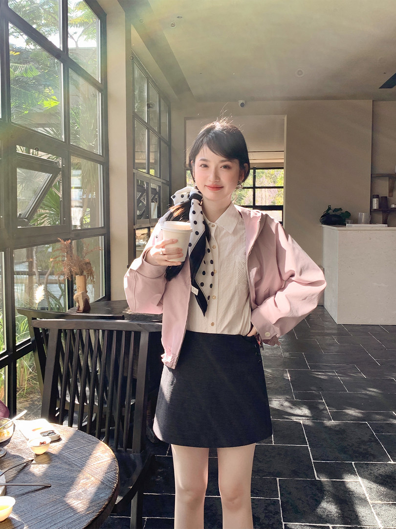 Woman wearing a pink jacket with a white blouse and black skirt