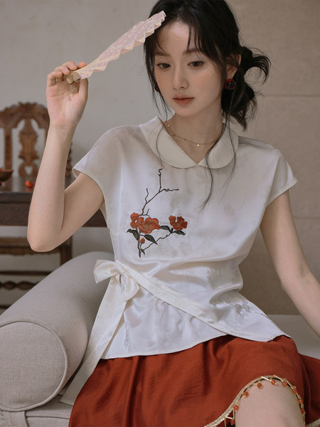 Woman modeling a white embroidered blouse with a rust-colored skirt