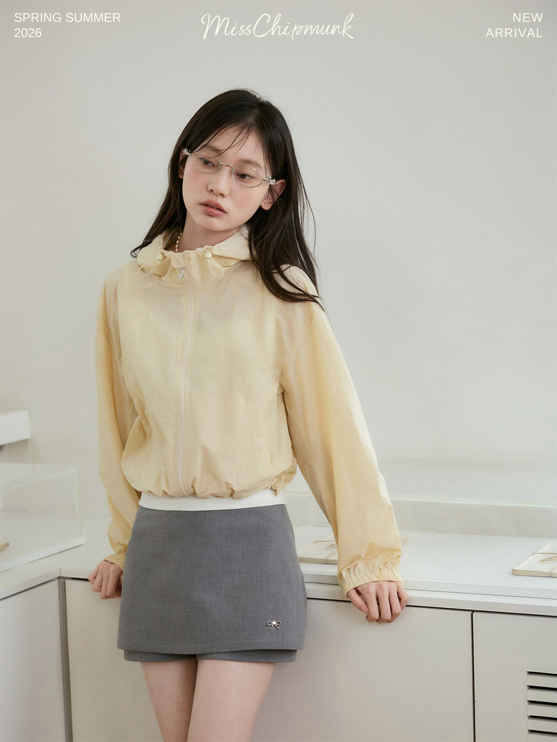 Model wearing a light yellow zip-up jacket with a gray mini skirt