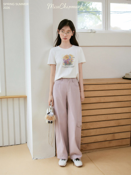 Model wearing a white graphic T-shirt and light pink cargo pants indoors