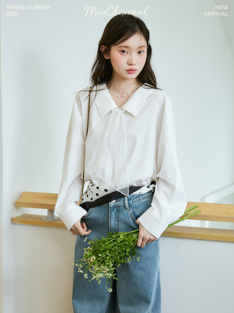 Model wearing a white blouse with jeans and holding a bouquet of flowers