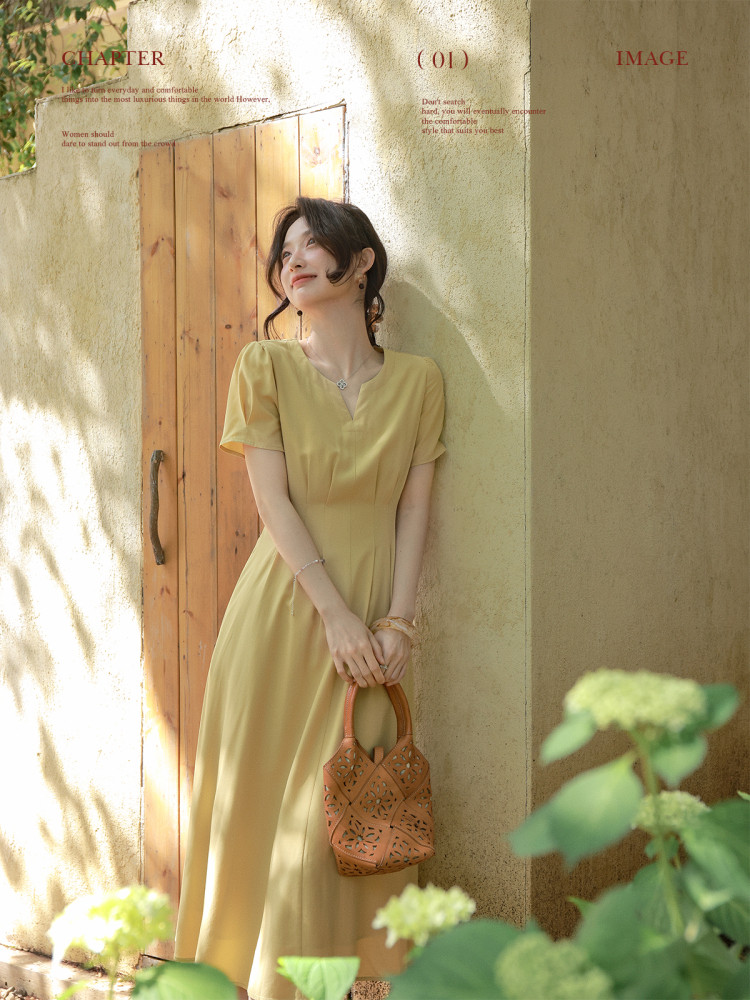 Woman wearing a yellow midi dress and holding a brown perforated handbag