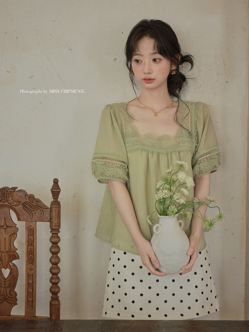 Model wearing a light green lace blouse with a polka dot skirt