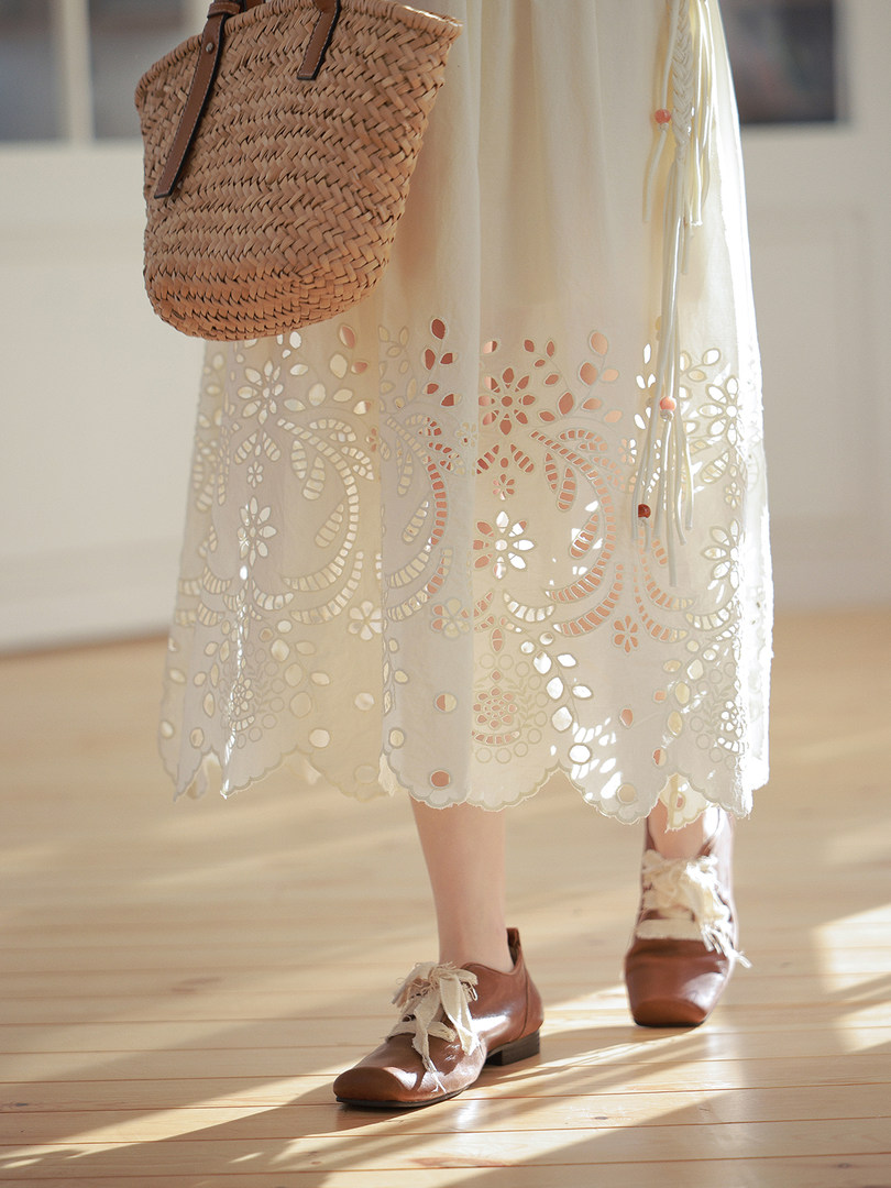 Cream lace cutout skirt or dress worn with brown shoes and woven bag