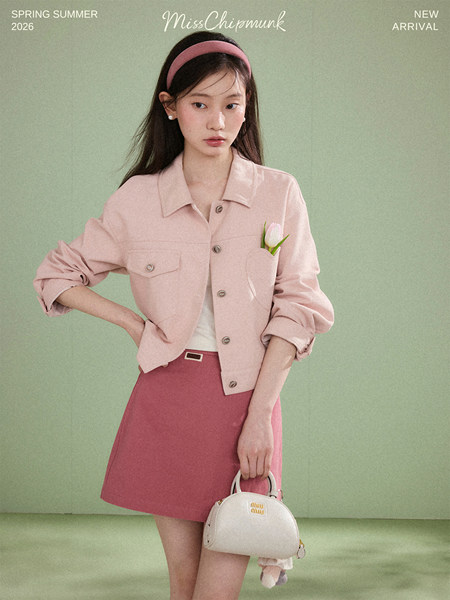 Model wearing a pink jacket and skirt holding a white handbag