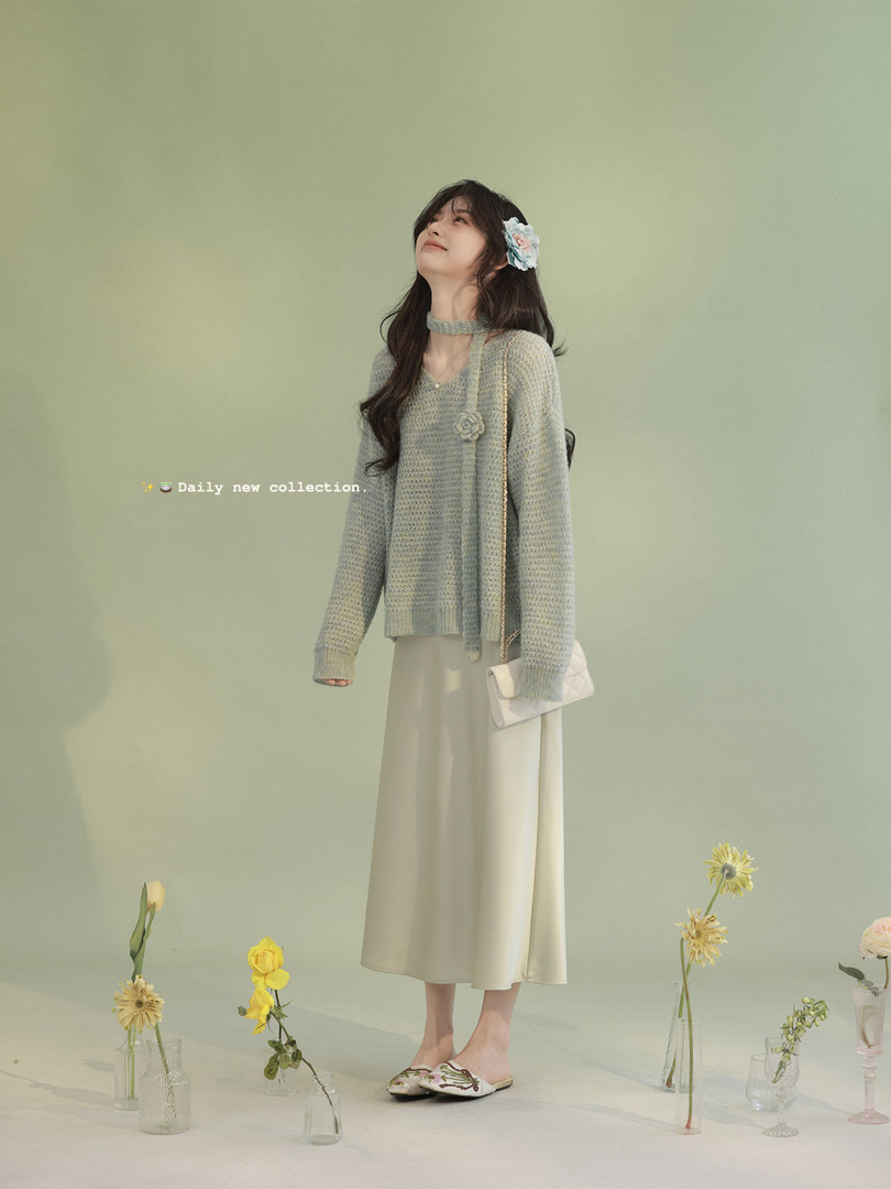 Model wearing a light knit sweater and cream midi skirt in a studio setting