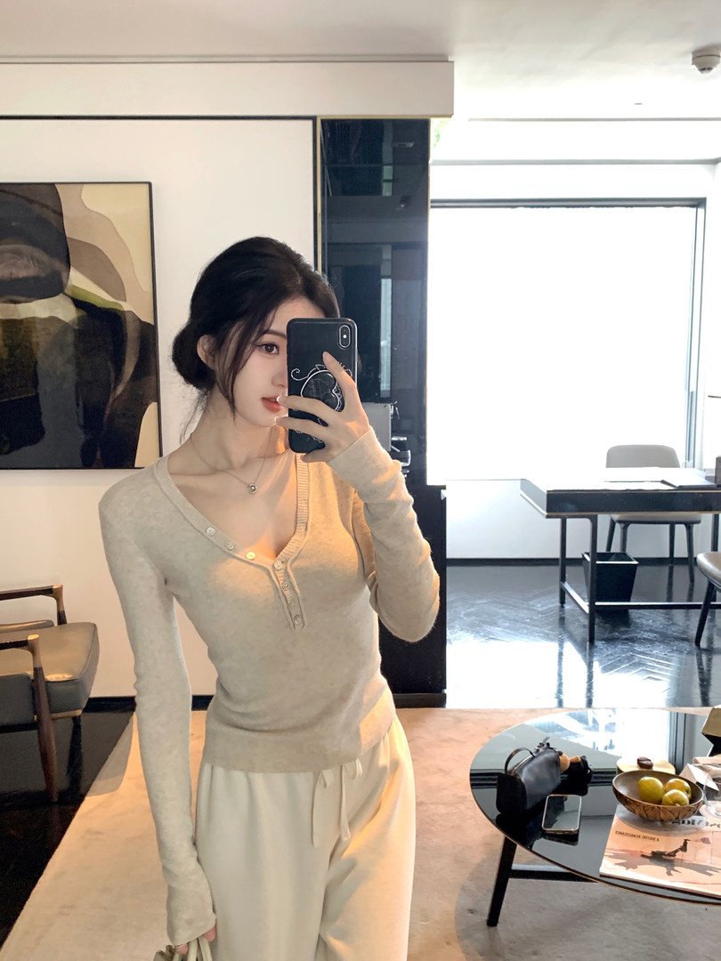 Woman taking mirror selfie wearing a beige long-sleeve V-neck knit top with buttons and matching pants