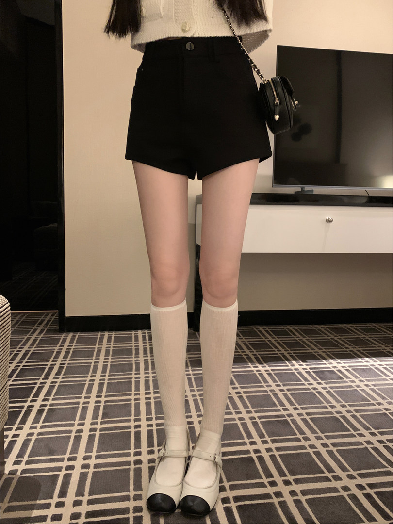 Black high-waisted shorts worn with a white top, knee socks, and Mary Jane shoes