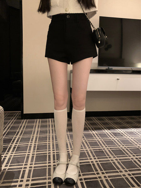 Black high-waisted shorts worn with a white top, knee socks, and Mary Jane shoes