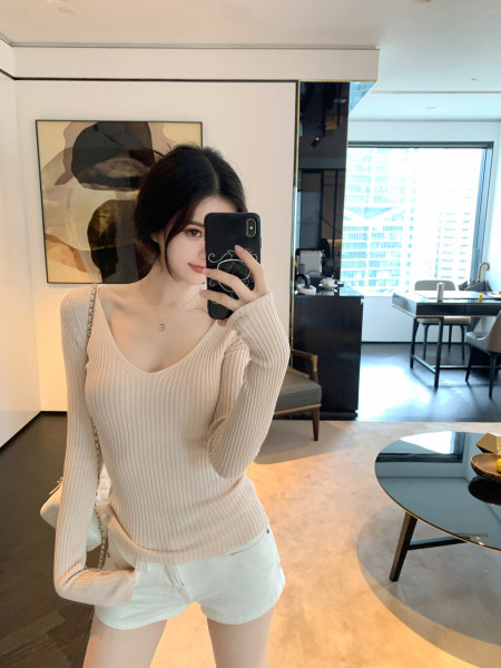 Woman taking mirror selfie wearing ribbed long-sleeve top and white shorts