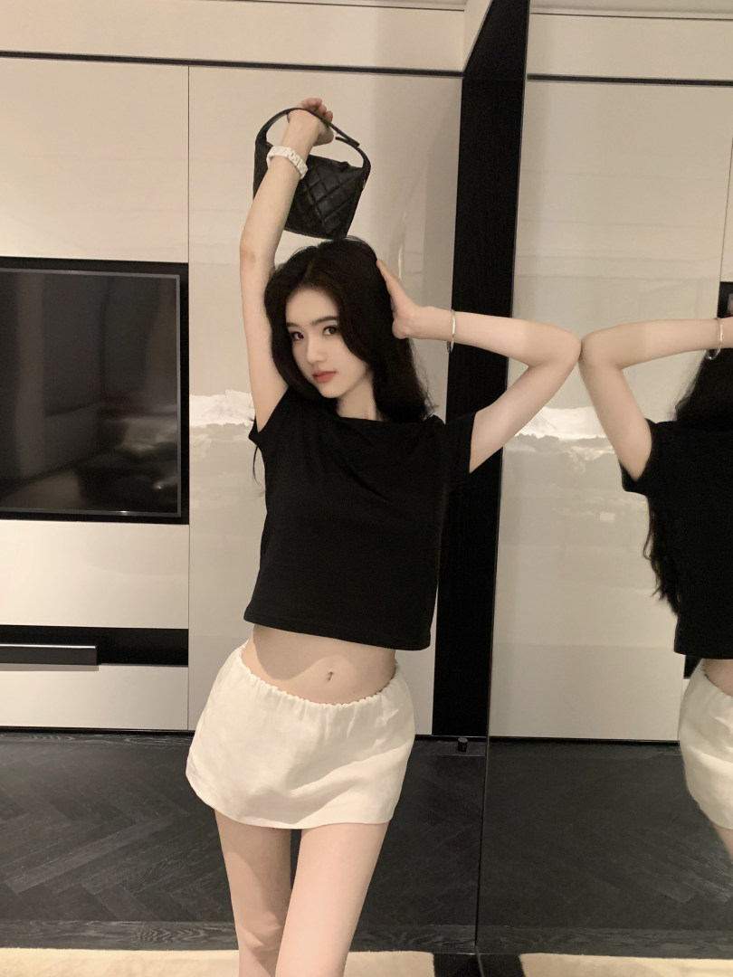 Woman wearing black crop top and white shorts holding a black handbag
