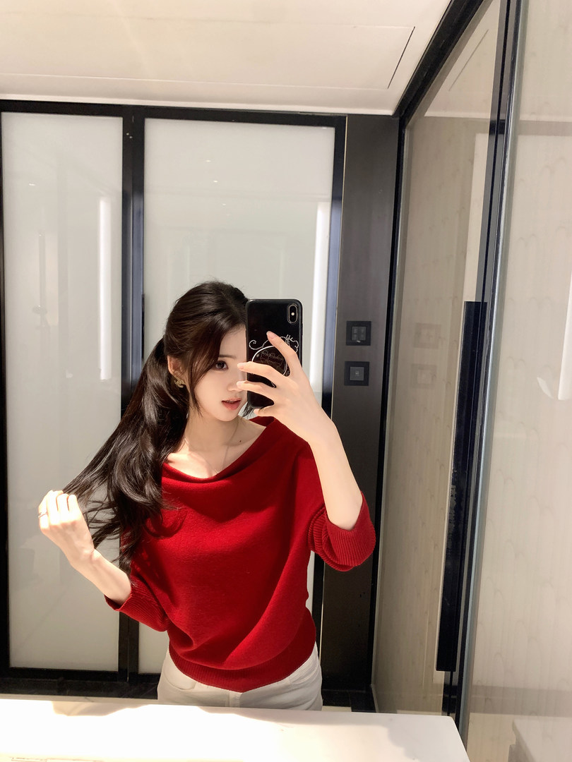 Woman taking mirror selfie wearing a red knit sweater