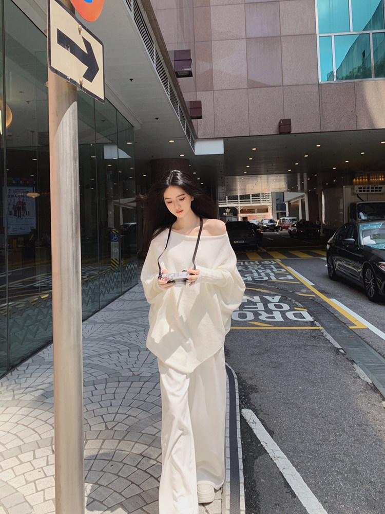 Woman wearing a white off-shoulder top and matching wide-leg pants on a city street.