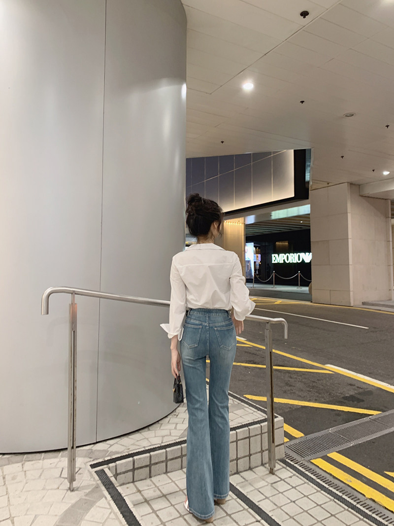 Woman wearing white blouse and blue flared jeans walking outdoors