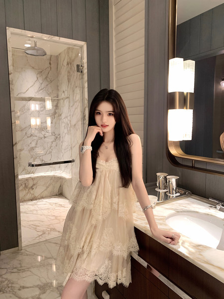 Woman wearing a beige lace dress in a marble bathroom