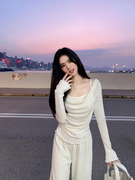 Woman wearing a white long-sleeve top and matching pants with a cityscape background