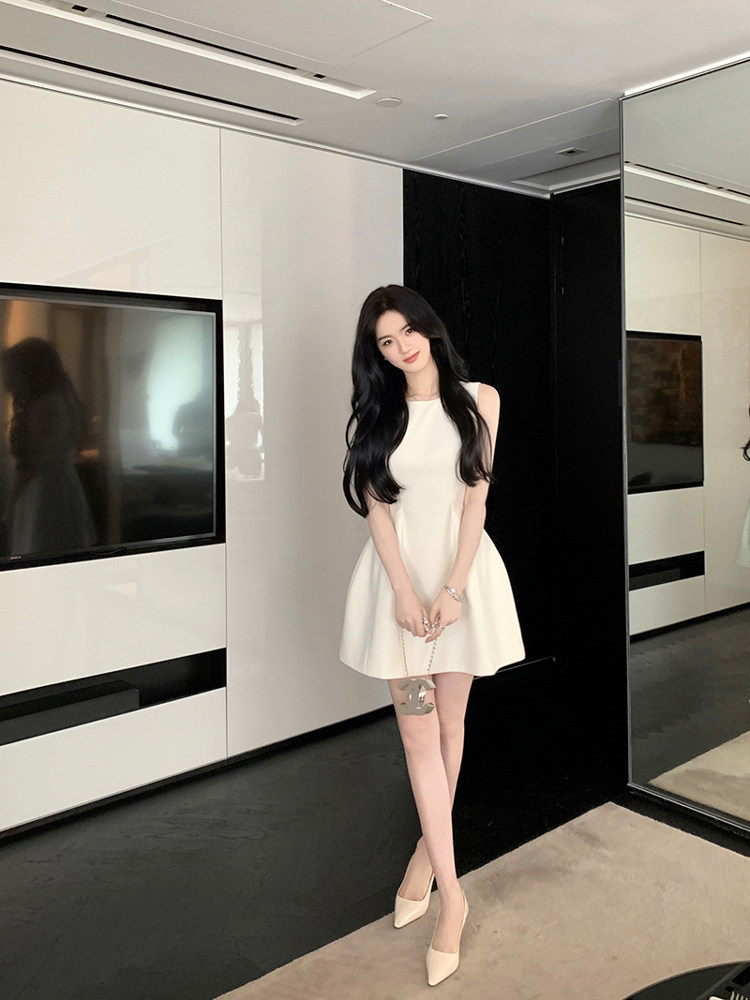Woman wearing a white sleeveless dress with high heels in a modern interior