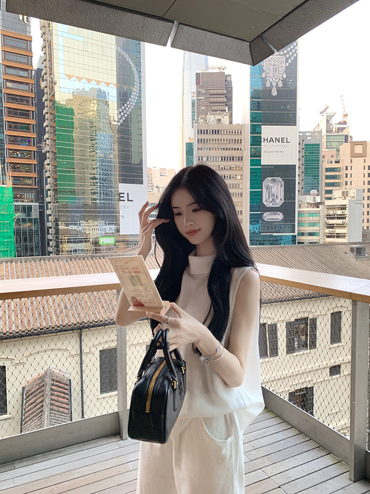 Woman holding a black handbag on a balcony with city skyline in the background