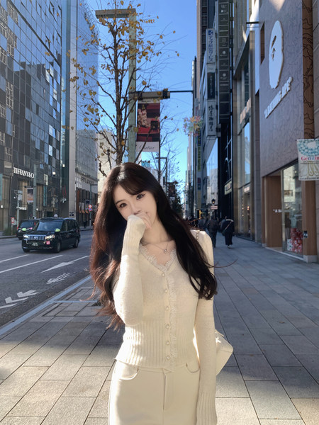 Woman wearing cream-colored knit cardigan and matching pants on a city street