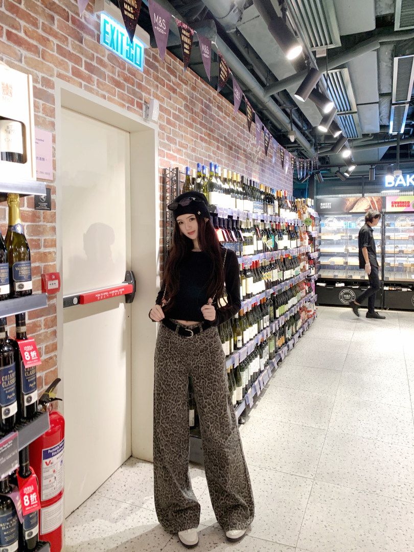 Woman wearing black top and leopard print pants in a store aisle