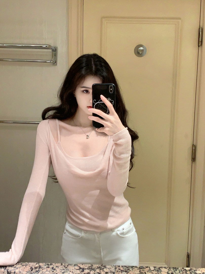 Woman taking mirror selfie wearing a light pink ribbed long-sleeve top with a wide neckline and white pants