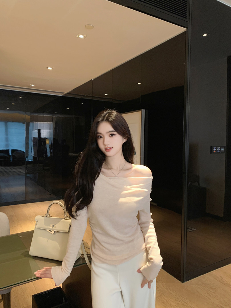Woman wearing off-shoulder top and white pants with a handbag on a table