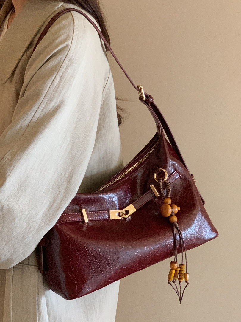 Burgundy leather shoulder handbag worn by a person