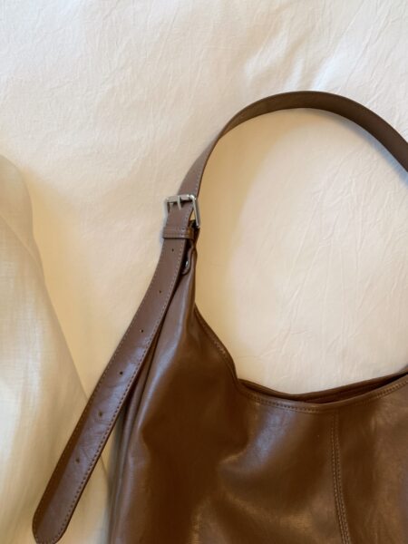 Brown leather shoulder bag with adjustable strap on a neutral background