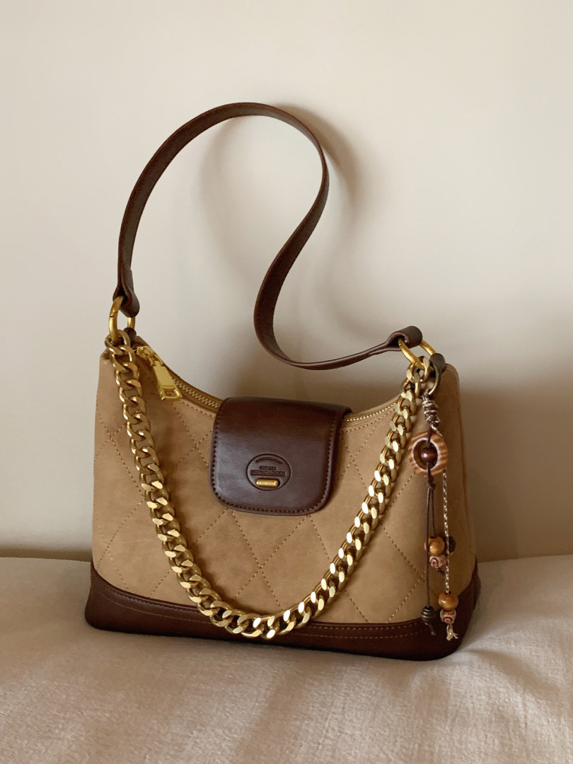 Brown and tan handbag with gold chain strap on a neutral background