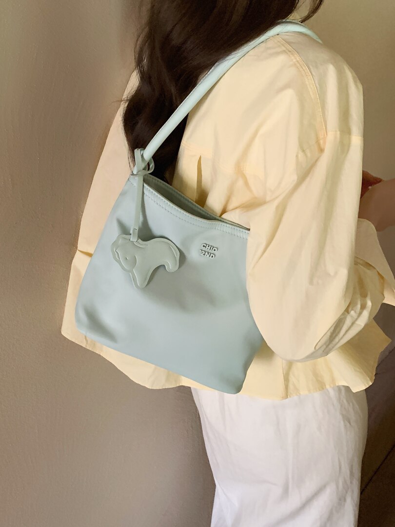 Light blue shoulder handbag worn over a cream outfit