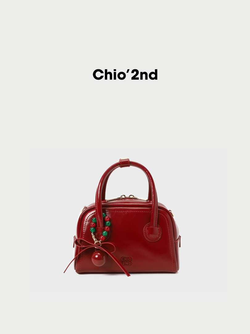 Red leather handbag with decorative beads on a white background