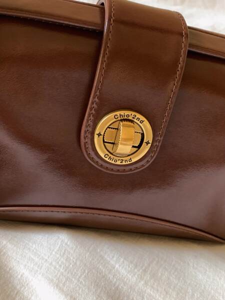 Brown leather handbag with a gold clasp close-up
