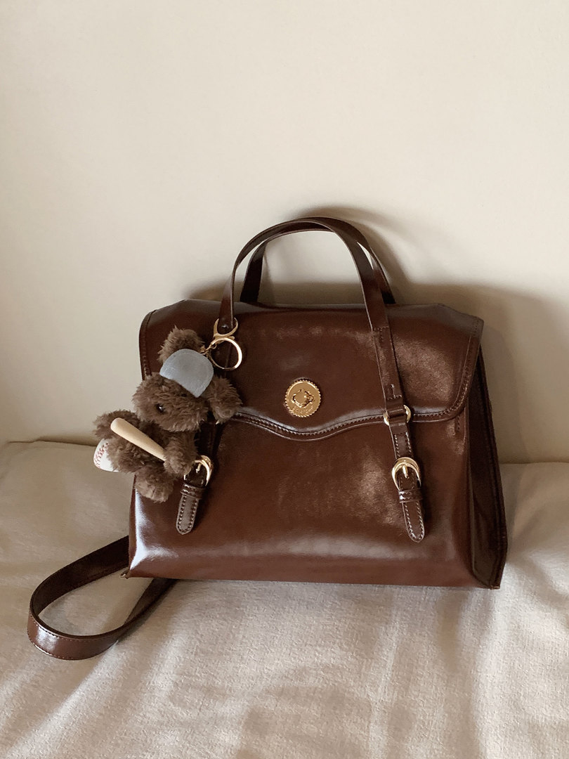 Brown leather handbag with shoulder strap and teddy bear charm