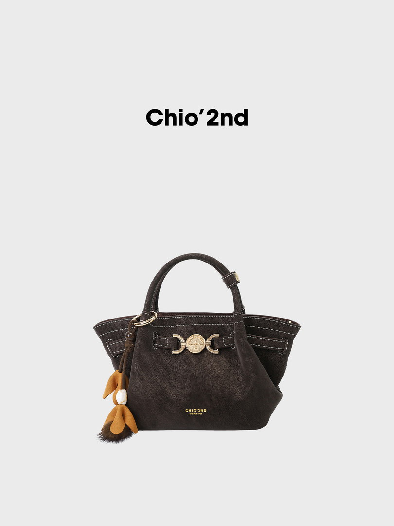 Dark brown leather handbag with gold hardware and charm accessory on a white background