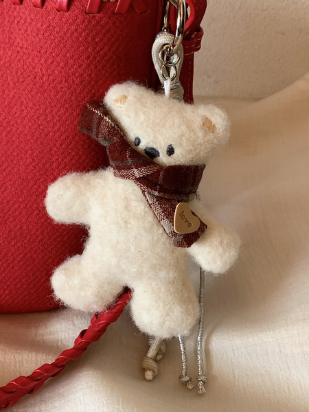 Plush teddy bear keychain charm with a plaid scarf and heart tag