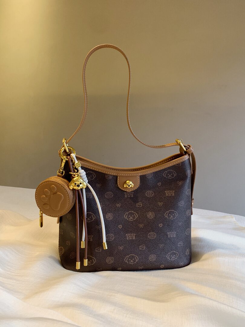 Brown monogram shoulder handbag with gold accents and charm accessory