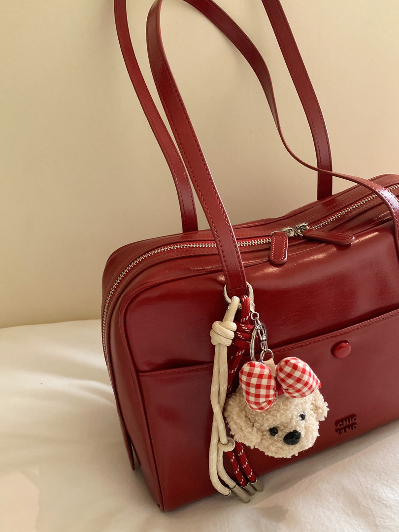 Red leather handbag with long straps and a teddy bear charm