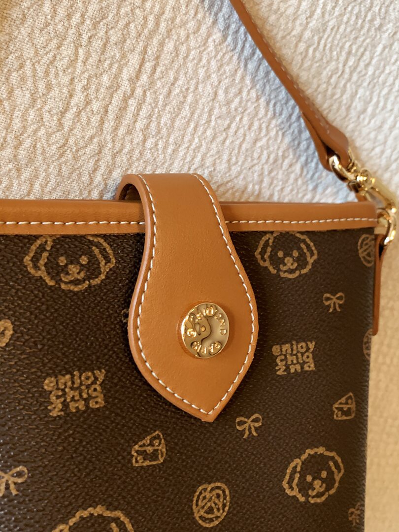 Close-up of a brown patterned handbag with tan leather strap and gold hardware