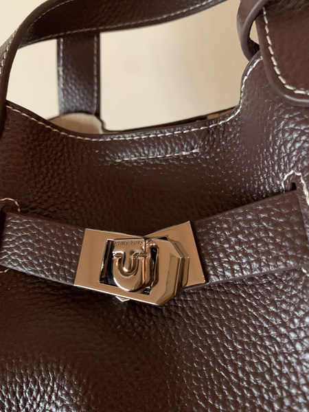Close-up of a brown leather handbag with a gold clasp