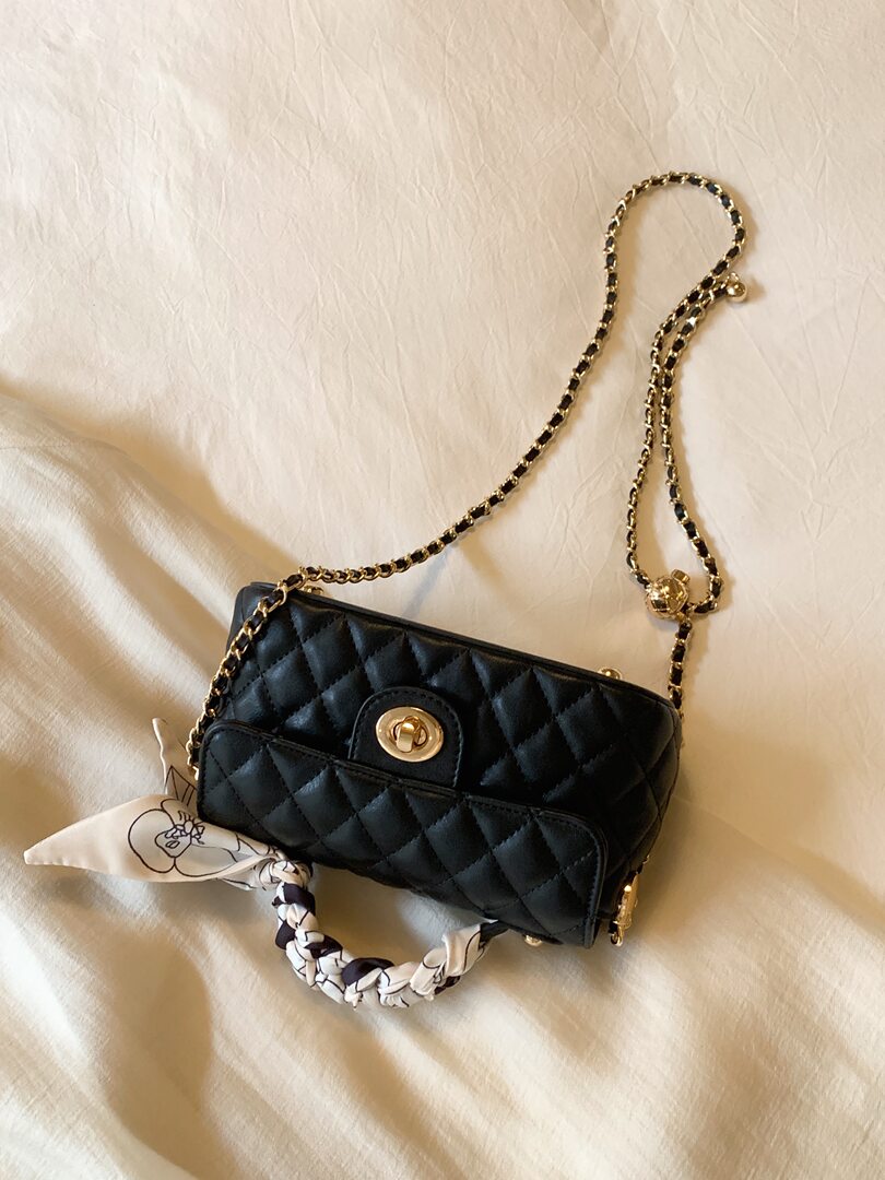 Black quilted chain-strap handbag with gold hardware and patterned handle scarf