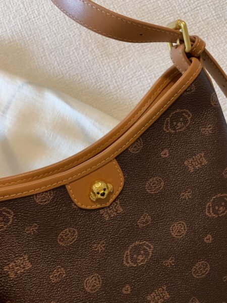Close-up of a brown monogram handbag with tan leather trim and gold hardware