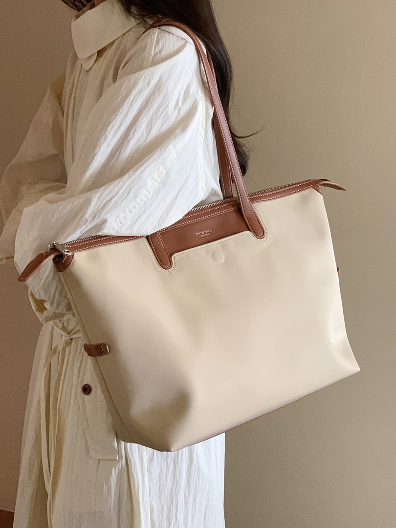 Cream and brown leather tote bag worn on a model