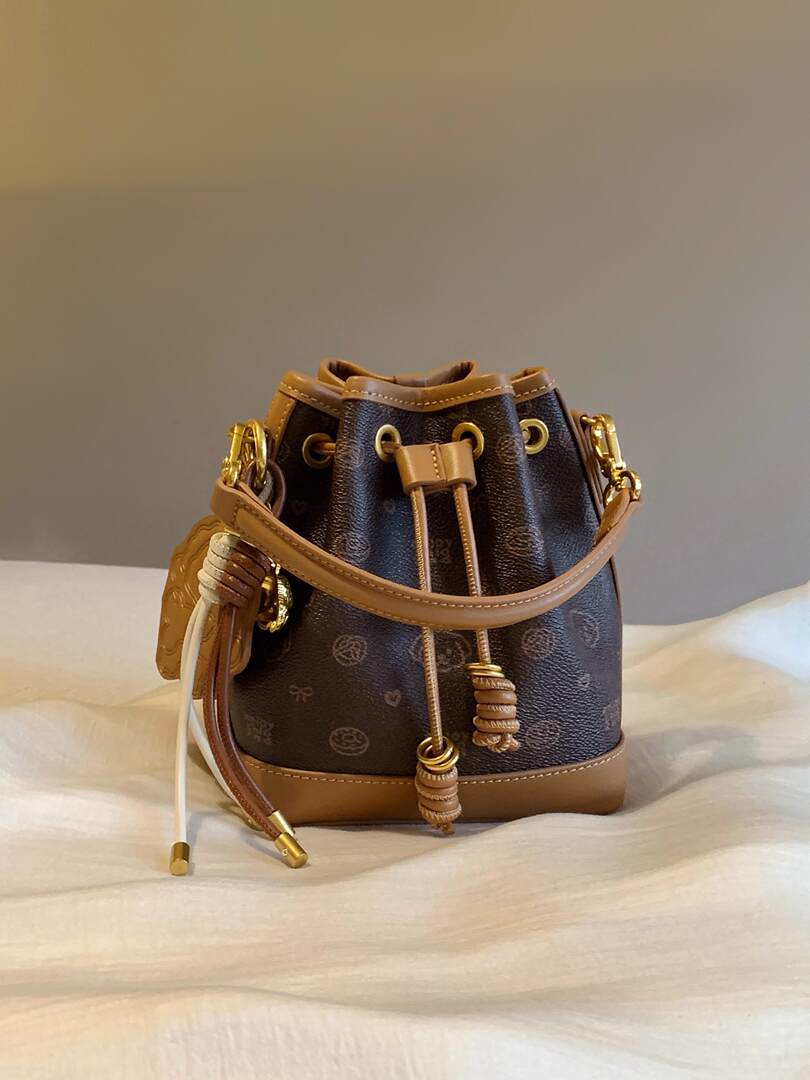 Brown and black drawstring handbag with gold-tone hardware on a light fabric background