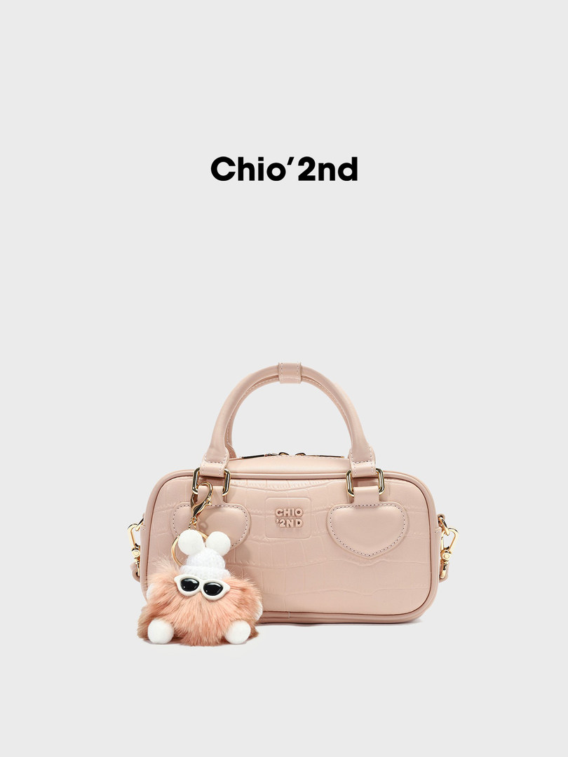 Pink structured handbag with a plush keychain charm on a white background