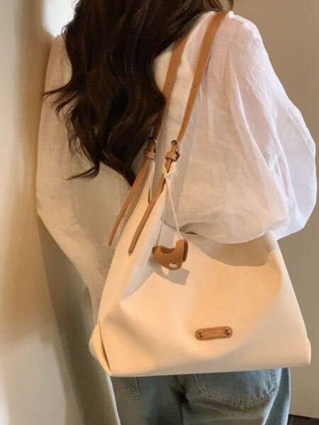 Cream shoulder tote bag worn by a woman