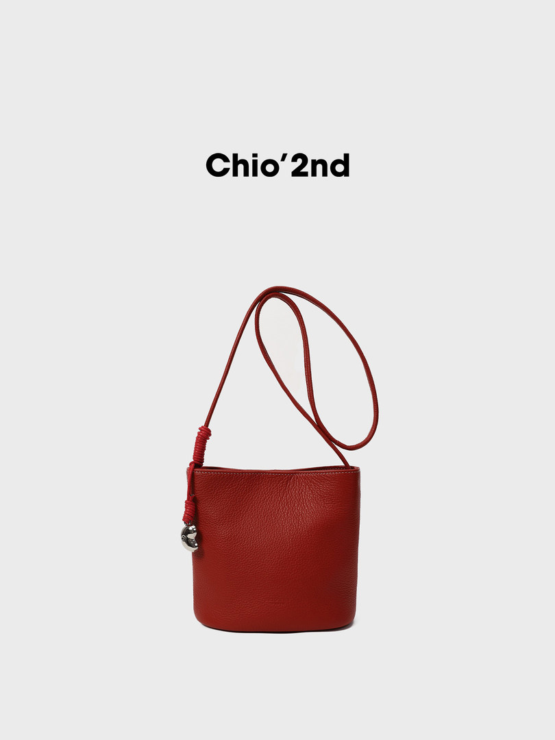 Red leather shoulder bag on a white background with brand text above